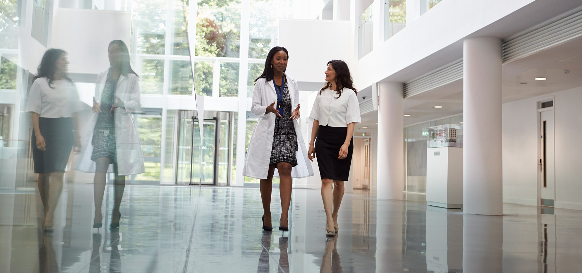Doctor and Business Woman Walking in Hall Of Medical Facility